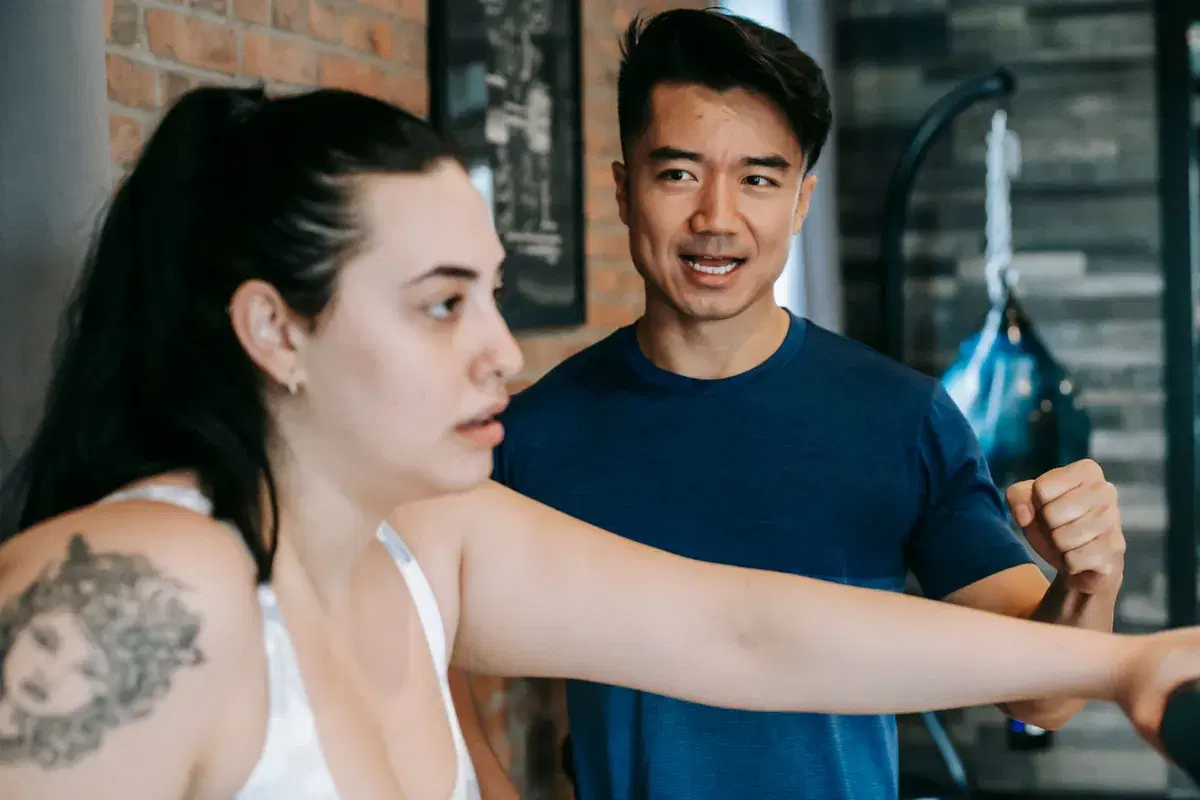 A coach guiding a client through a lift, correcting form mid-rep